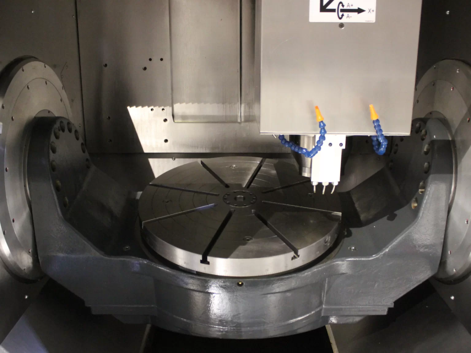 Close view of a five-axis cradle table showing the two rotary axes and the mounting face