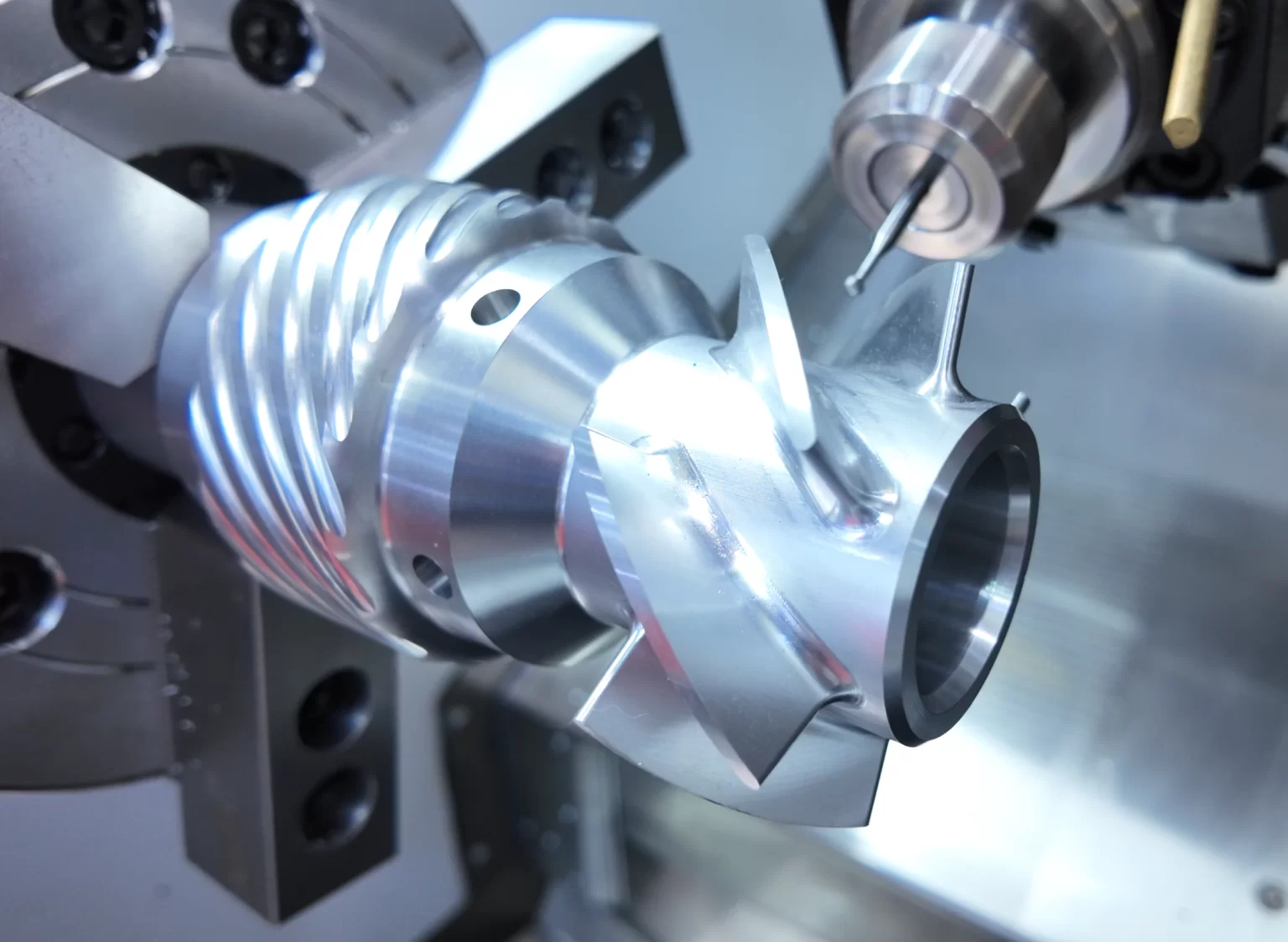 A finish-machined part held in a CNC lathe chuck with the turret tool at the cutting position